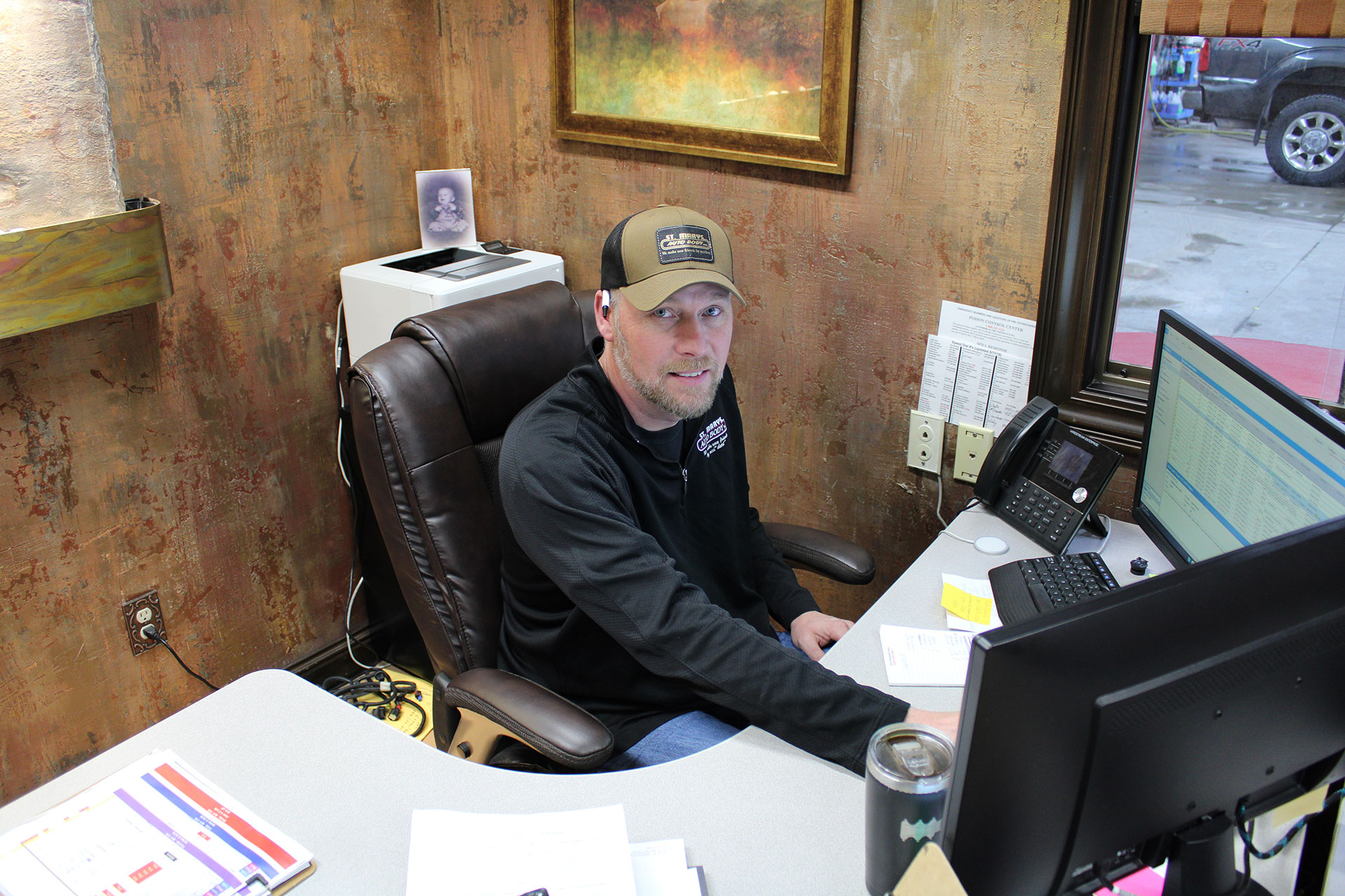 A Photo of the manager Ryan sitting at his desk smiling | St Mary's Auto Body